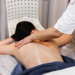The girl in the spa salon receives a back and neck massage, lies in the cosmetology table, relaxed and enjoys the process