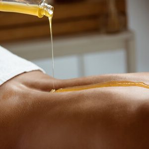 Honey pouring on girl's naked back in spa salon. Copy space.